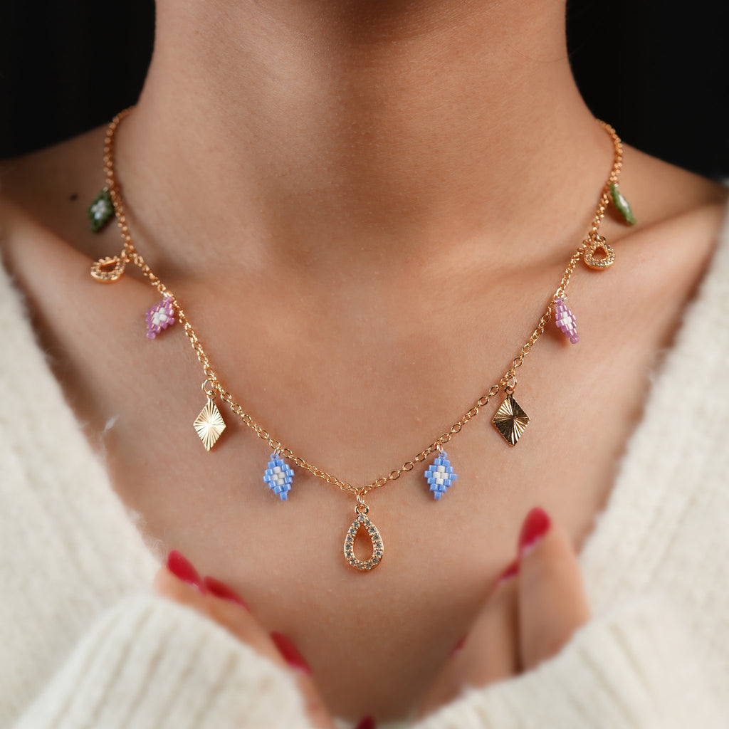 Model wearing rose-gold necklace with pastel beaded rhombus charms and sparkling teardrop drops