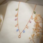 Angled view of pastel beaded rhombus, sunburst rhombus and crystal teardrop charms on rose-gold chain
