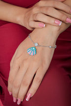 Pastel seashell charm bracelet on the wrist with bezel-set crystal stations on silver chain