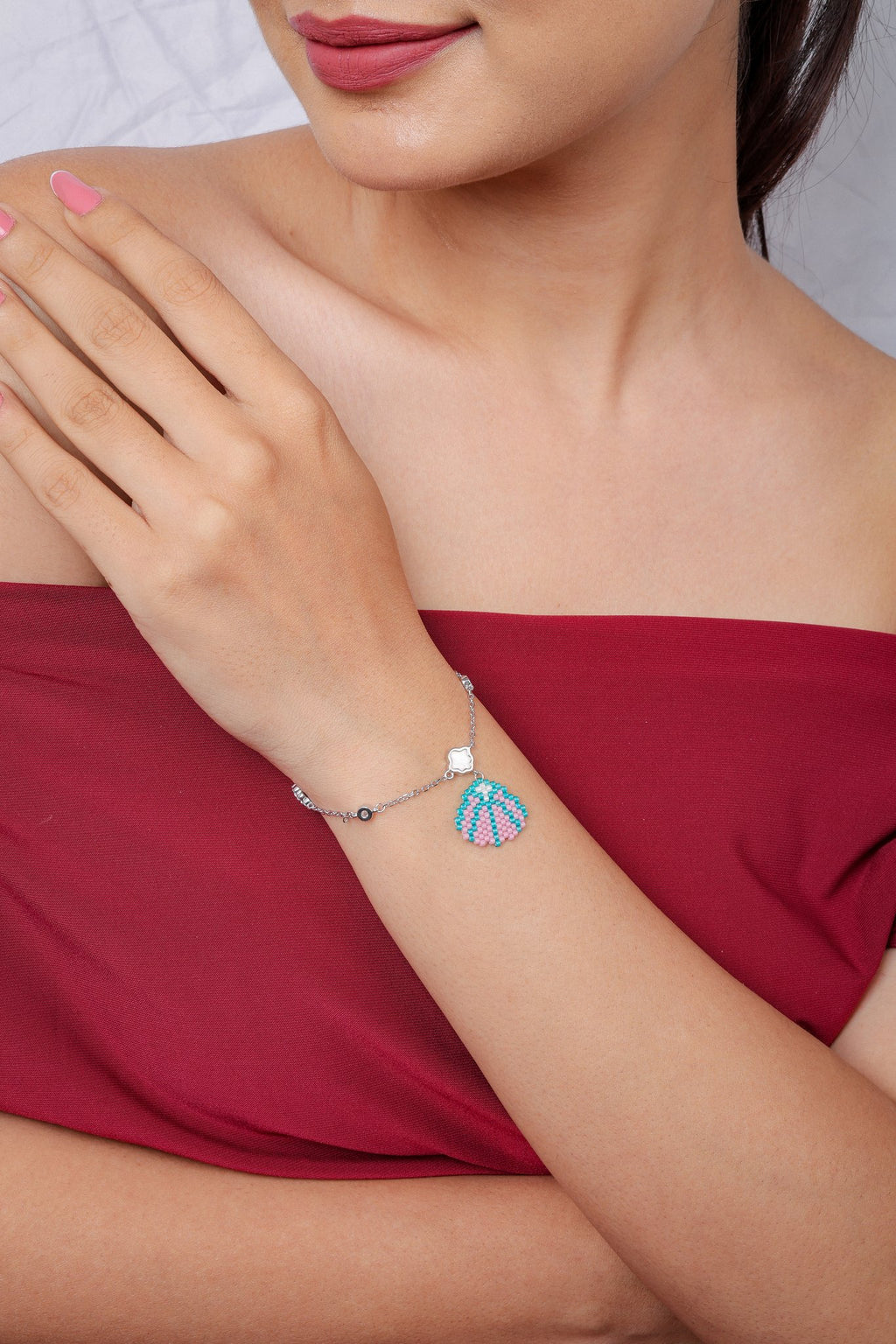 Model in red off-shoulder dress wearing silver seashell charm bracelet