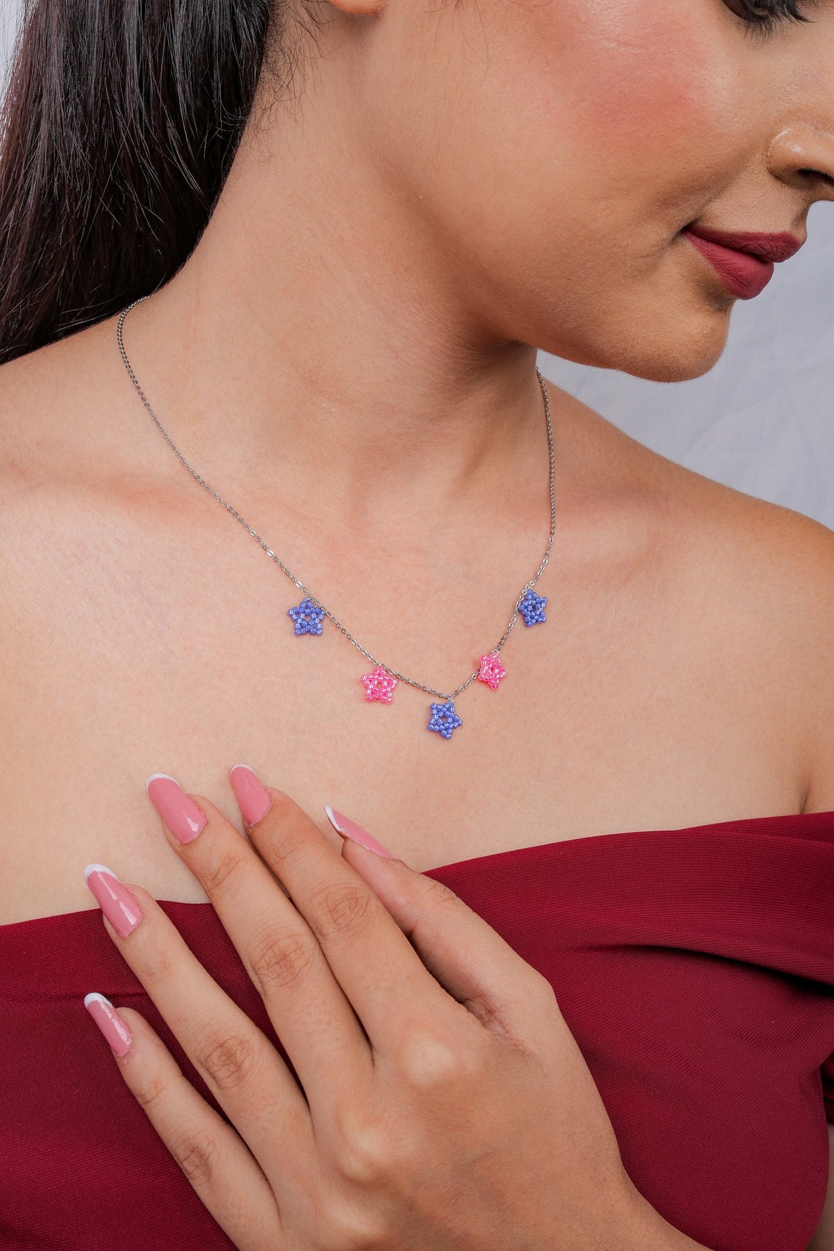 Model wearing silver necklace with periwinkle and pink beaded star charms