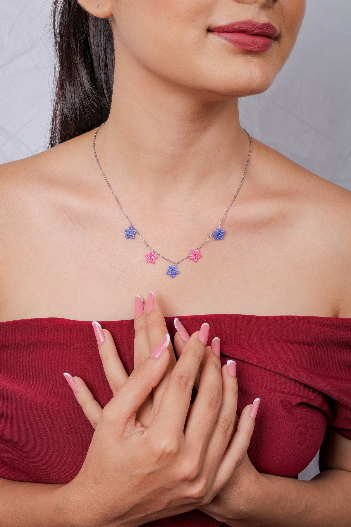 Front view of silver star charm necklace in periwinkle and pink on model