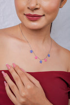 Model smiling with hand on chest, wearing dainty periwinkle and pink star necklace