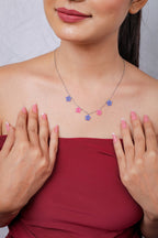 Model framing the necklace with both hands, silver chain with five beaded stars