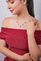 Model in red off-shoulder top gazing down, wearing dainty silver star charm necklace