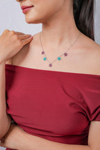 Model with hand on shoulder wearing silver necklace with plum and teal beaded stars