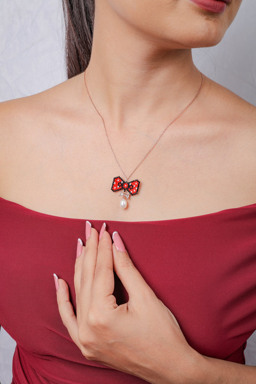 Rose-gold chain necklace with red polka-dot beaded bow pendant, crystal bow and pearly drop