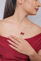 Model in a red off-shoulder top wearing the polka-dot bow pendant necklace