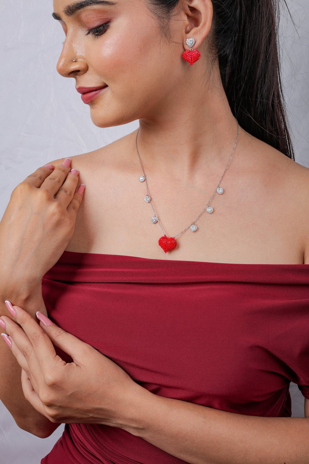 Model wearing the puffed red beaded heart necklace with crystal drops and matching heart earrings