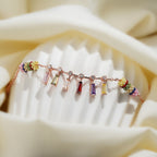 Angled view of rose-gold bracelet with colourful baguette drops and striped bead barrels