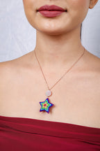 Front view of a model wearing a rainbow star pendant with a red off-shoulder top