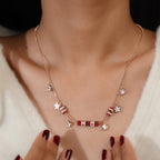 Model wearing rose-gold necklace with red beaded barrels and clear crystal flower charms