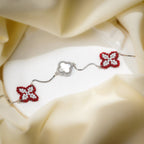 Silver box-chain bracelet with two red and white beaded clovers and a crystal-framed white clover