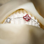 Red clover charm bracelet on a silver box chain draped over a white stand