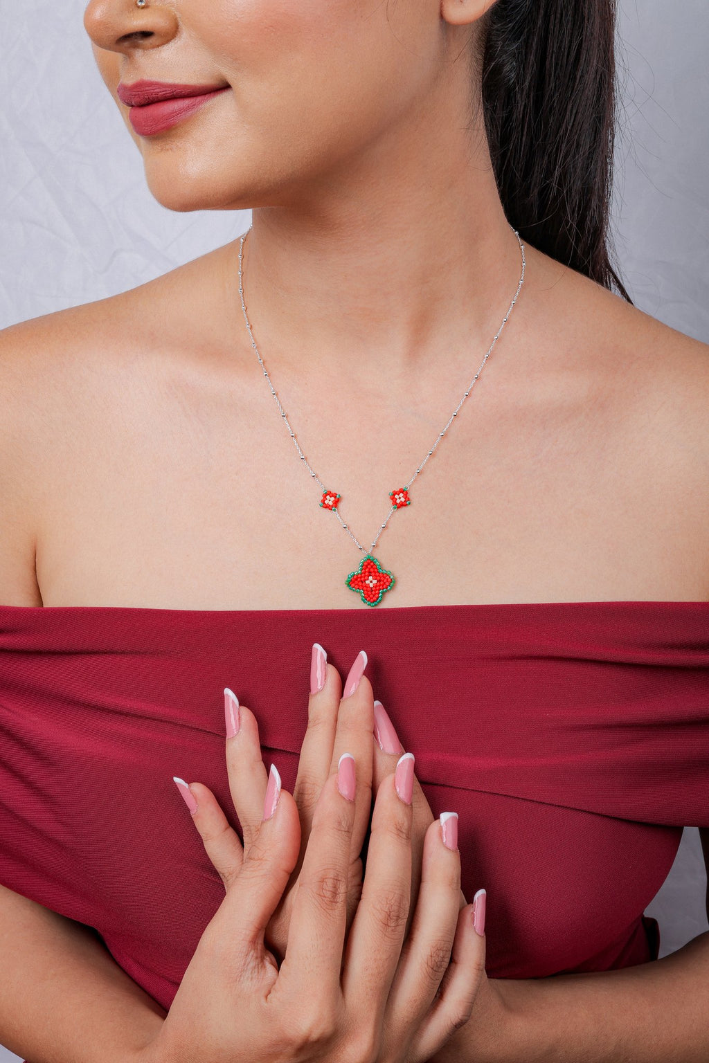 Front view of red beaded clover pendant necklace on the model with matching mini flower charms