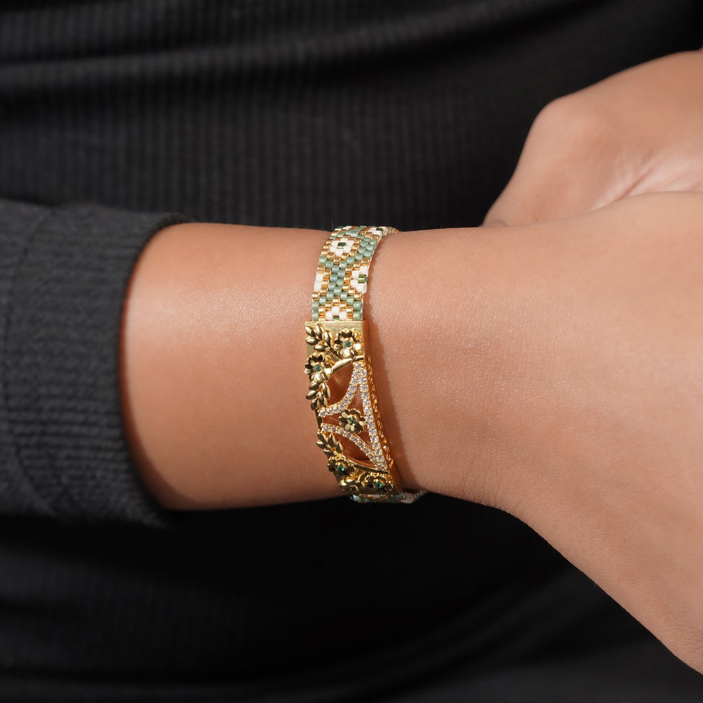 Model wearing the sage green woven bead cuff with gold floral plate on the wrist