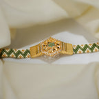 Sage green and cream zigzag woven bead bracelet with gold hexagon centrepiece on cream fabric