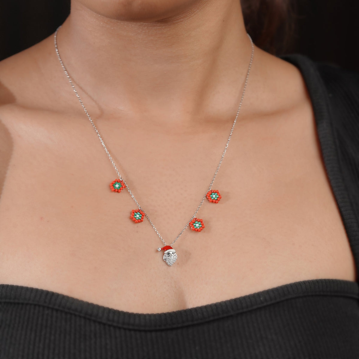 Model wearing silver Christmas necklace with beaded red flowers and Santa pendant