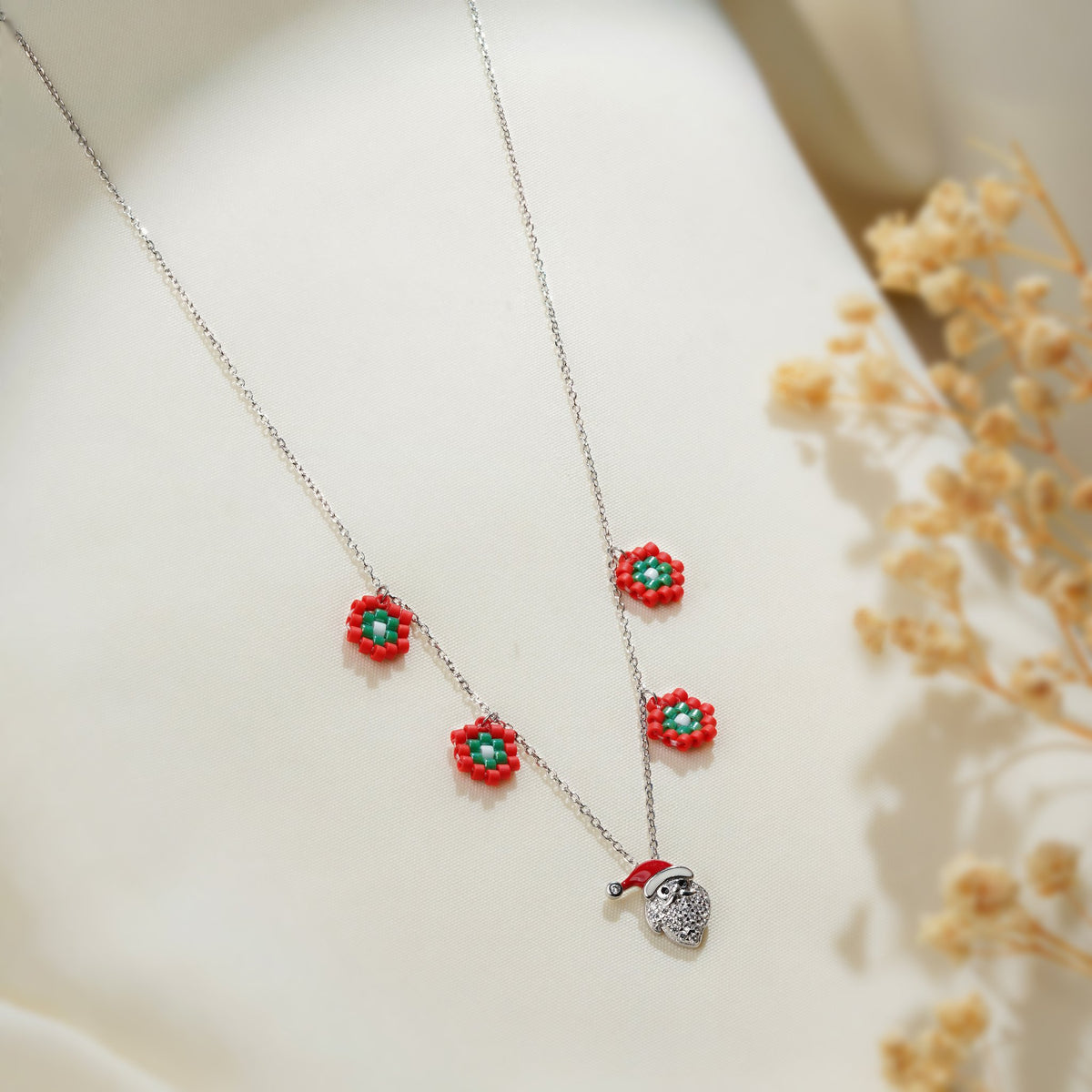 Close-up of red beaded flowers with green centres and sparkling Santa face charm