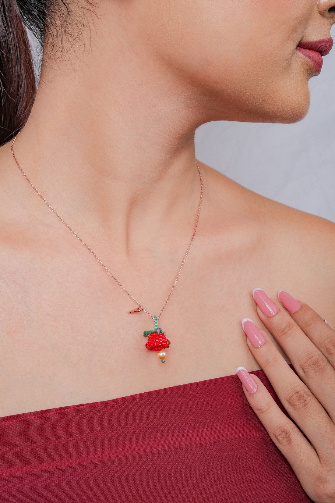 Rose-gold chain with a red beaded bloom pendant, green leaves, pearl-look drop and tiny key charm