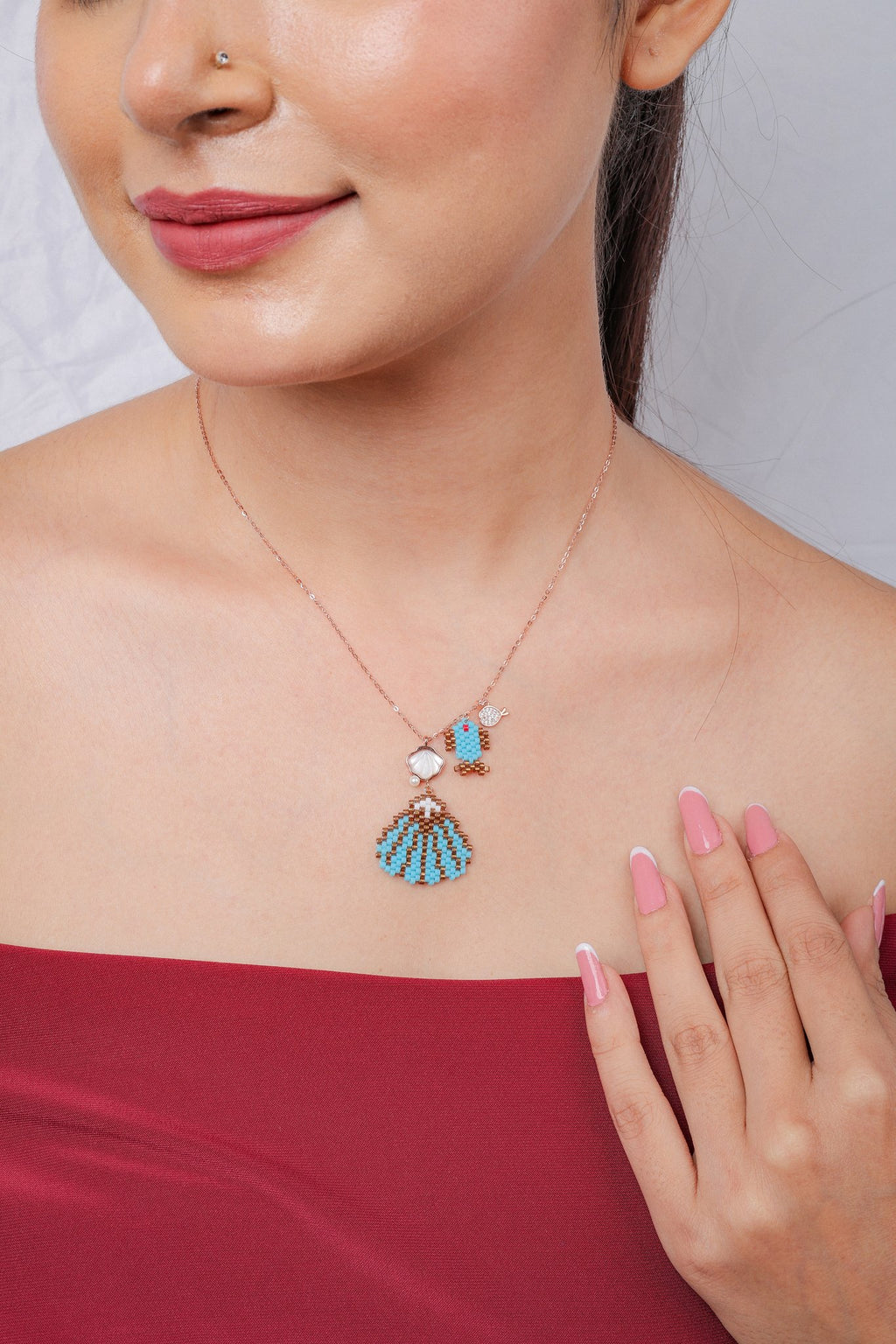 Rose-gold necklace with turquoise beaded seashell, pearly shell charm, beaded fish and crystal fish