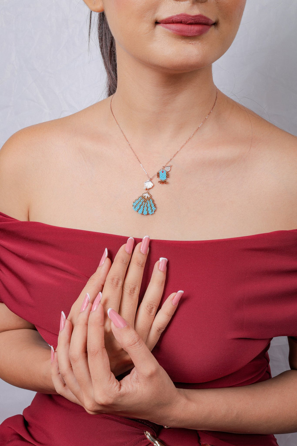 Model wearing rose-gold seashell cluster necklace with hands clasped at chest