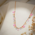 Rose-gold chain necklace with pink beaded squares and rose-gold and silver sunburst heart charms