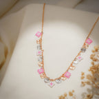 Rose-gold chain necklace with pink beaded squares and rose-gold and silver sunburst heart charms