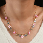 Model wearing the pink beaded square and two-tone heart charm necklace at the collarbone
