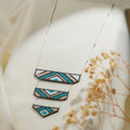Silver chain necklace with three tiered beaded panels in teal, sand, white and grey chevrons