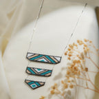 Silver chain necklace with three tiered beaded panels in teal, sand, white and grey chevrons