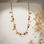 Gold charm necklace with terracotta and white beaded barrels, star charms and crystal drops
