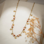 Angled view of gold chain with terracotta and white beaded barrels and brushed gold star charms