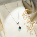 Silver lariat necklace with crystal-winged angel connector and turquoise beaded pyramid drop