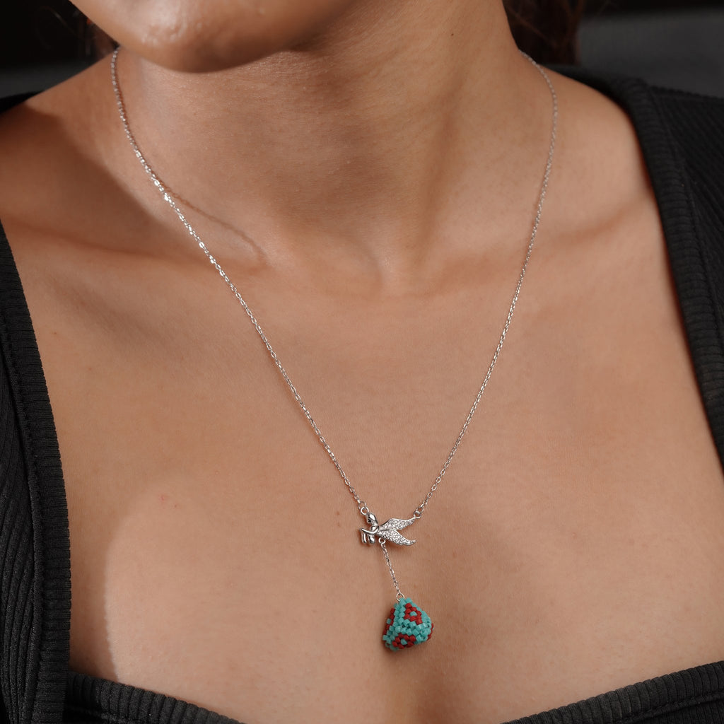 Model wearing silver Y-necklace with sparkling winged angel and turquoise beaded drop