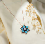 Rose-gold-tone chain with a large turquoise beaded five-petal flower pendant, pearly centre