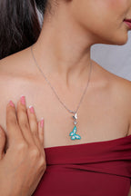 Silver chain necklace with turquoise and white beaded butterfly drop beneath silver butterfly charms