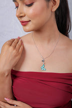 Model looking down, wearing the turquoise butterfly drop pendant on a silver chain
