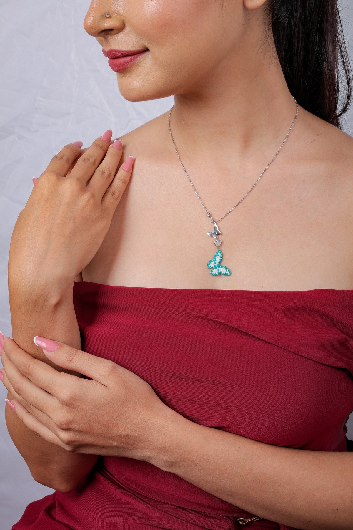 Side view of the turquoise and white beaded butterfly pendant on a fine silver chain