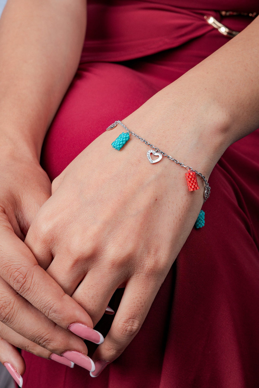 Silver chain bracelet with turquoise and coral beaded tube charms and open heart charms on the wrist