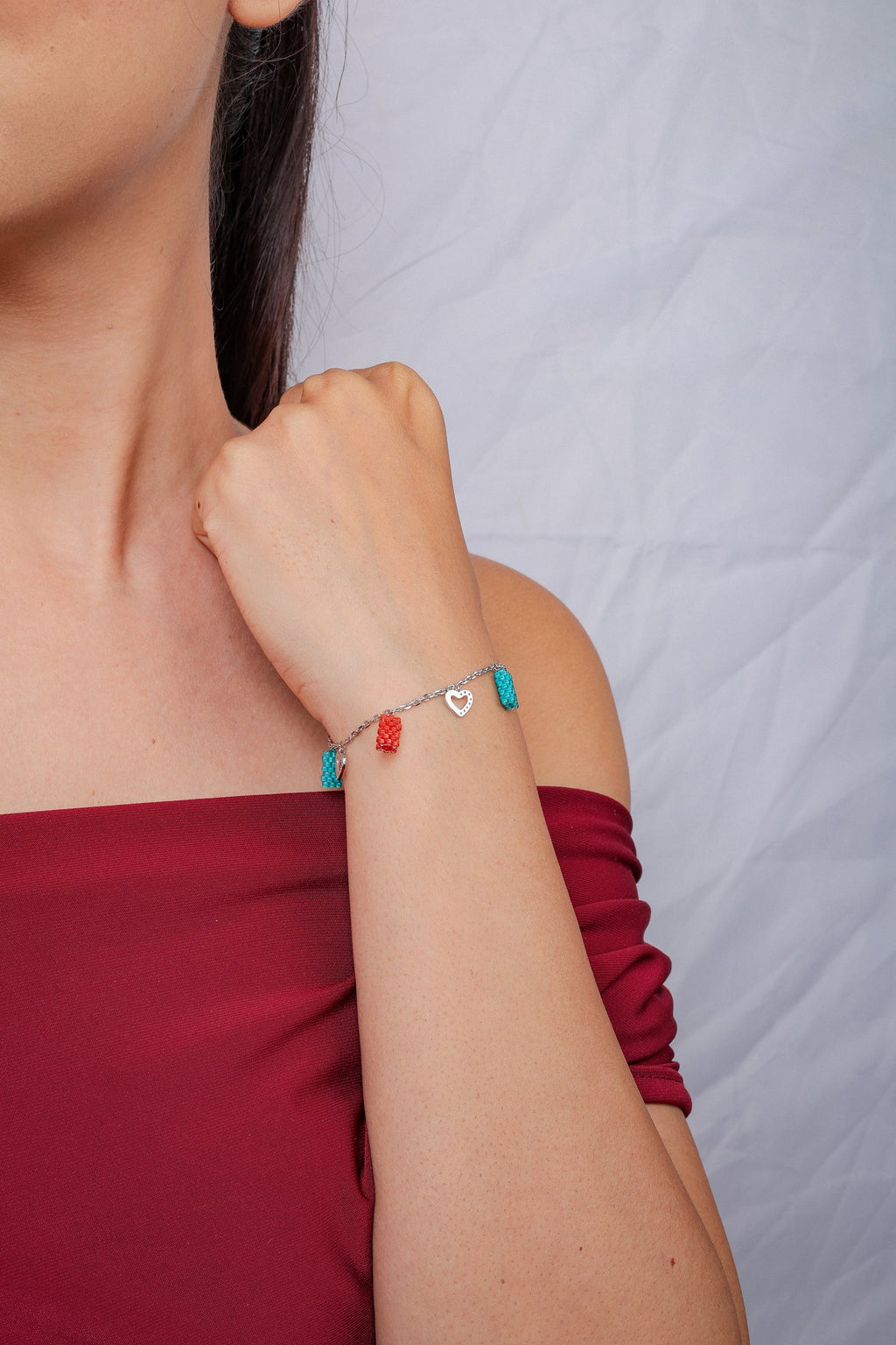 Model wearing the turquoise and coral charm bracelet with her fist raised to the shoulder