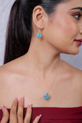 Model wearing silver necklace with turquoise beaded cube pendant and matching drop earring