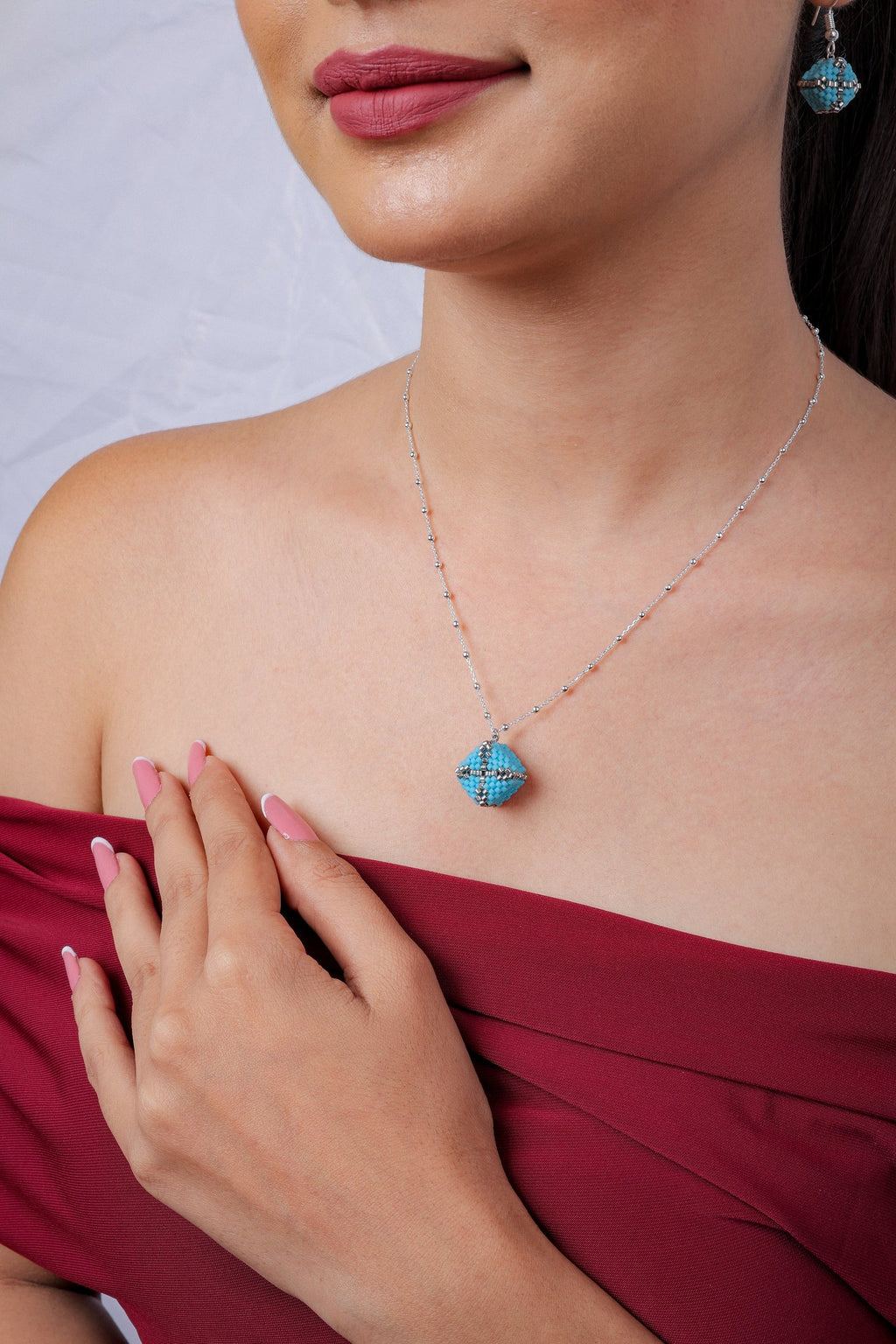 Turquoise beaded cube pendant on silver satellite chain with matching earring, worn by model