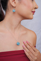 Side profile showing turquoise cube drop earring and matching pendant on silver chain
