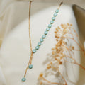 Gold-tone lariat necklace with a row of turquoise beaded daisies and two daisy drops