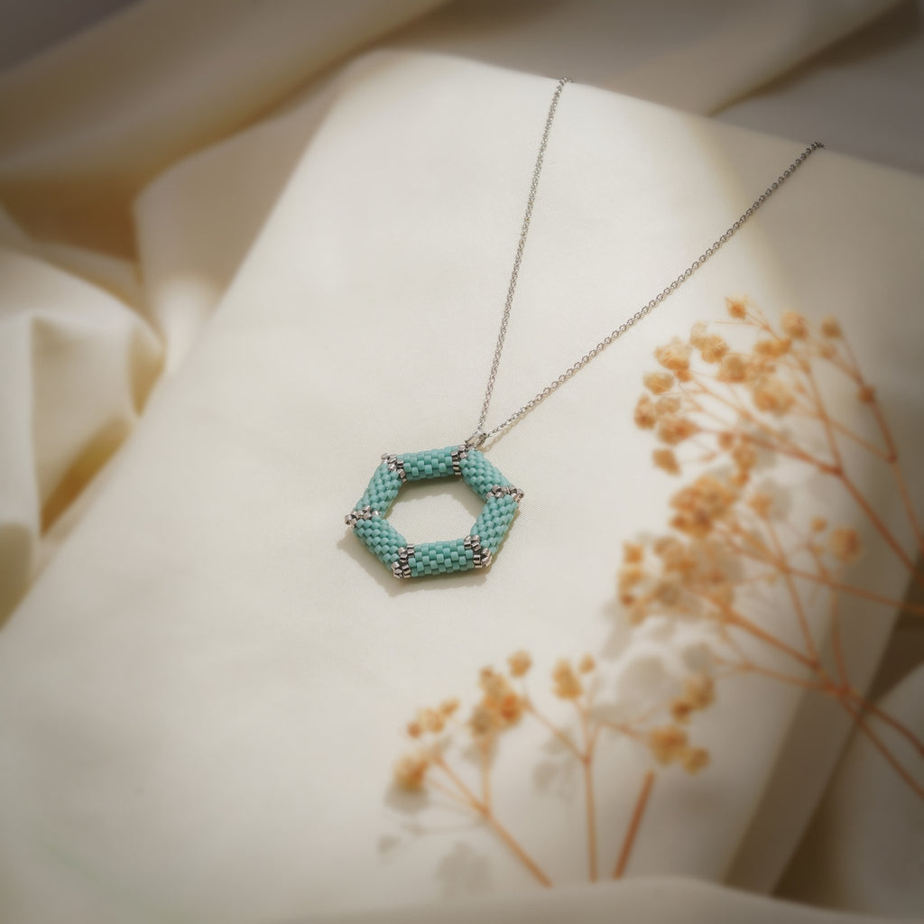 Turquoise hexagon pendant on a silver-tone chain beside dried gypsophila