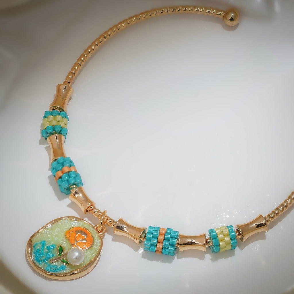Close-up of shimmering disc charm with orange rose, green leaves and a pearly bead