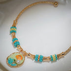 Close-up of shimmering disc charm with orange rose, green leaves and a pearly bead