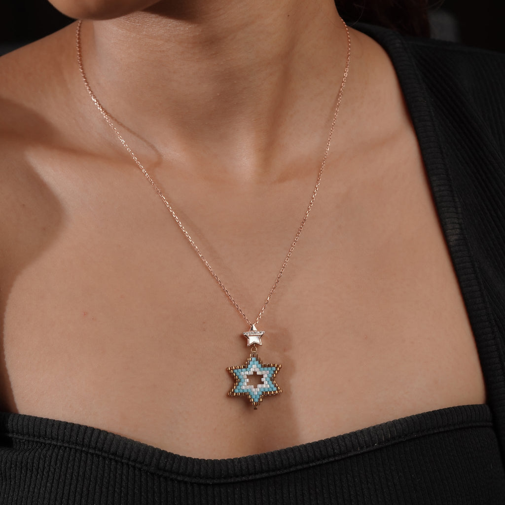 Model wearing rose-gold chain with turquoise beaded star pendant and small star bail