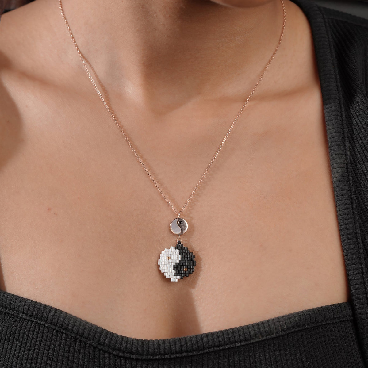 Model wearing rose-gold chain with beaded black and white yin-yang pendant